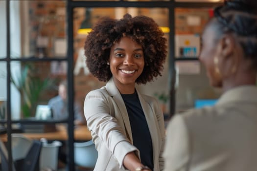 A woman and a man in a suit shake hands in a professional setting.