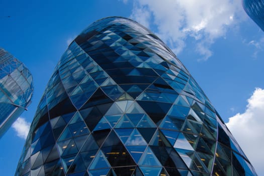 A very tall building with a multitude of windows reaching towards the sky. The structure stands out in the urban landscape, reflecting sunlight and casting shadows on the surrounding area.