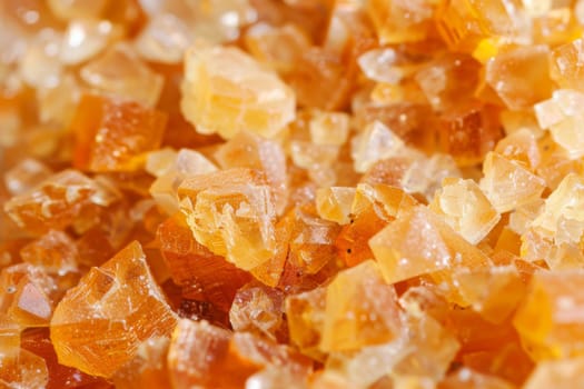 A close-up view of a cluster of bright orange crystals, showcasing their vibrant color and unique textures. The crystals are stacked on top of each other, creating a visually striking composition.