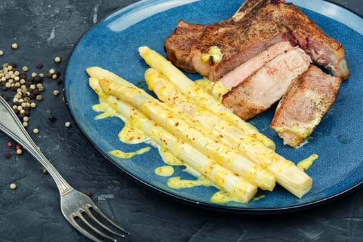 Fried meat steak and garnish of asparagus. Roast meat with vegetables.