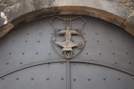 Fortress metal door with rivets. Old medieval castle in Kotor, Montenegro. Entry iron door with pattern. Medieval style with rivets of steel. Forged figure of a man, a fire and a boiling vessel.