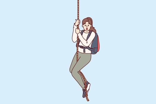 Frightened woman climber hangs on rope and opens mouth from fear, or release of adrenaline in body. Girl engages in extreme sports and is fond of hiking for sake of adrenaline hormone.