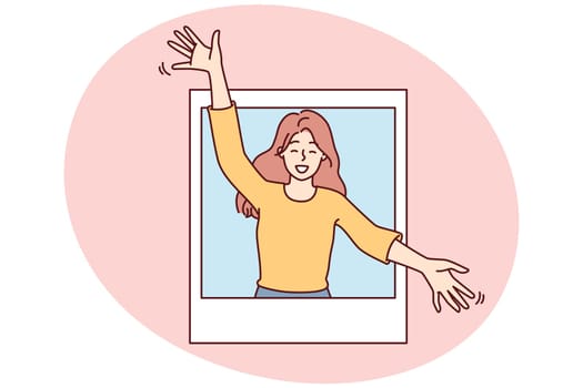 Delighted woman peeks out of photo with arms apart to hug you and give good mood. Attractive girl in casual clothes rejoices at meeting or wishes to hug goodbye
