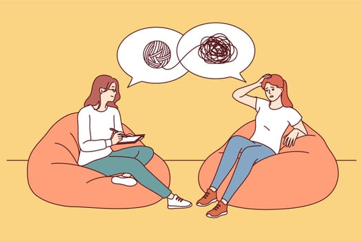 Session of psychotherapist helping girl patient understand confused thoughts and solve psychological problems. Female psychotherapist sits on ottoman opposite woman with mental disorder