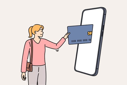 Woman mobile banking user inserts credit card into large phone to make purchase in online store. Concept of online payment for goods on website or application thanks to digital banking