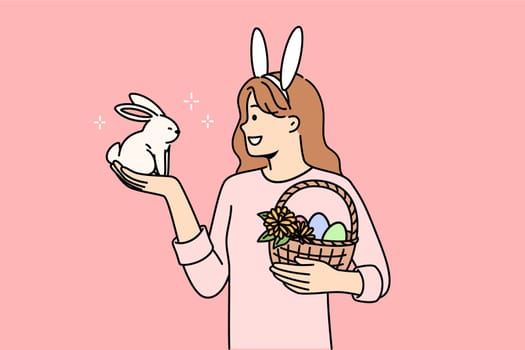 Teenage girl celebrating easter holds decorated eggs in basket and small rabbit, rejoicing at coming of spring. Schoolgirl is preparing for easter and bringing traditional gifts to friends from school