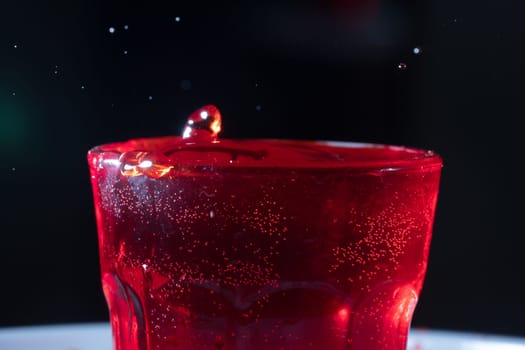 drops of red liquid in glass beaker