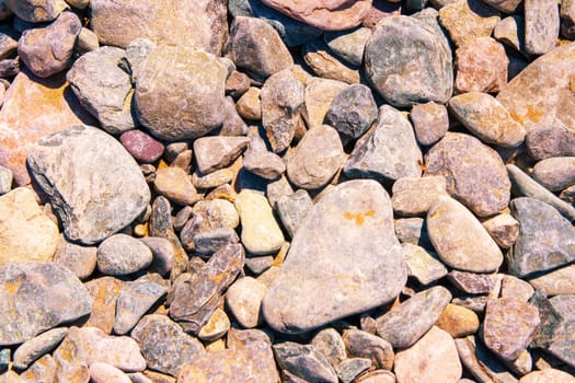 Stone texture background. Close-up of natural sea gravel or pebbles at summer beach with selective focus. Natural design backdrop for your project.