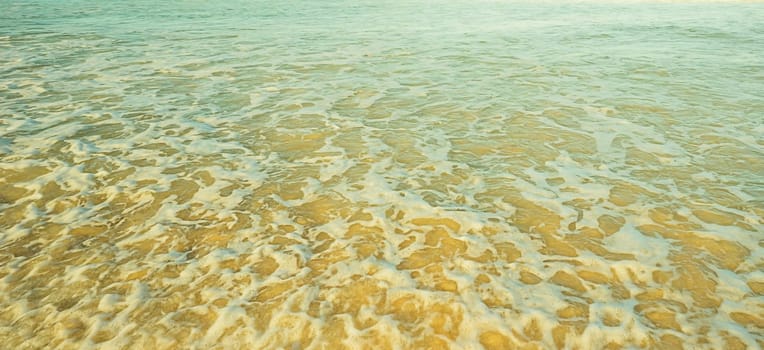 Ocean background of shallow sea water foaming and churning sand