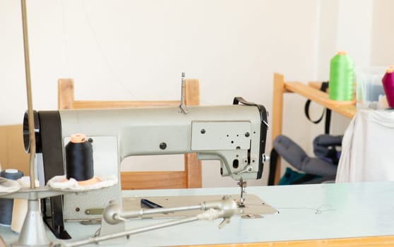 Industrial sewing machine with colorful thread, working place, manufacture for clothes, handmade, small local business