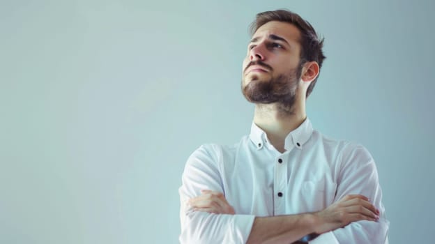 A man standing with his arms crossed, gazing upward with a concentrated expression. He appears contemplative and deep in thought, possibly reflecting on something important.