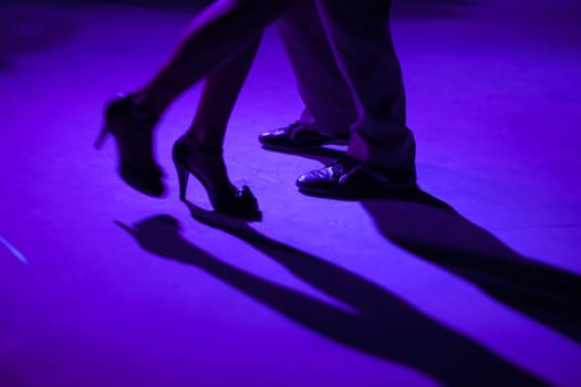 Tango dancers in milonga ballroom, detail of shoes.