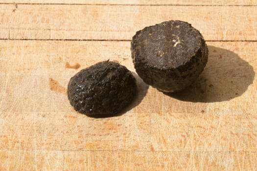 Tomato and black truffle isolated on a wooden cutting board
