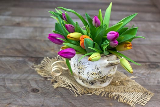 colorful tulips in a vase - old wooden background