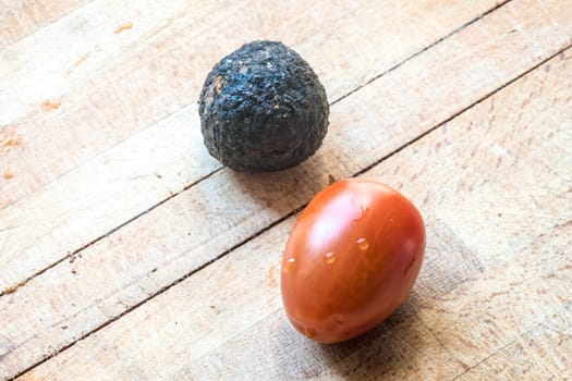 Tomato and black truffle isolated on a wooden cutting board