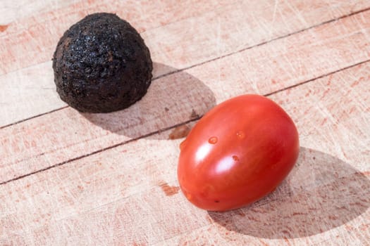 Tomato and black truffle isolated on a wooden cutting board