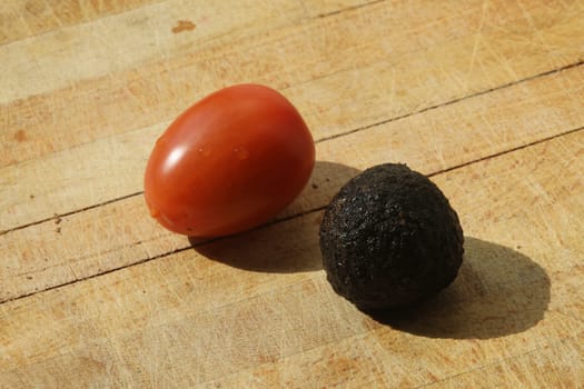Tomato and black truffle isolated on a wooden cutting board
