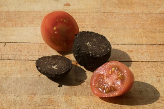 Tomato and black truffle isolated on a wooden cutting board