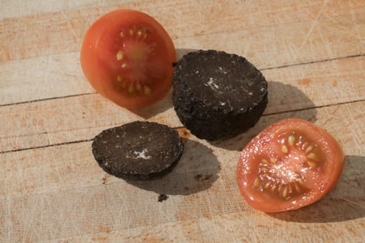 Tomato and black truffle isolated on a wooden cutting board