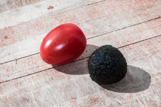 Tomato and black truffle isolated on a wooden cutting board