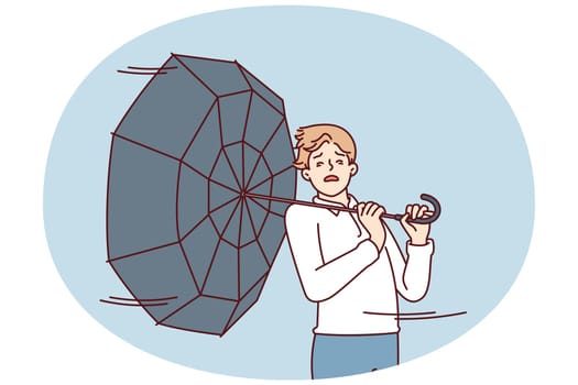 Man with umbrella turned backwards walks down street during severe life-threatening storm. Pedestrian in casual clothes caught in hurricane walking around city and needs shelter