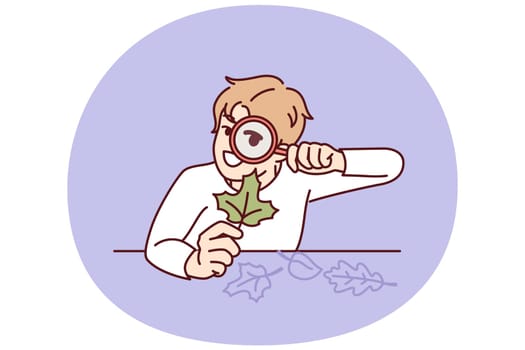 Teenage boy with magnifying glass examines leaf from tree, studying plants and wishing to work in botanical field. Curious boy elementary school student with tree leaf doing homework from teacher