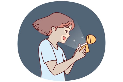 Little girl opens golden box and is delighted to see contents shining and illuminating child face. Teenage girl with gift box rejoices at adorable birthday present that evokes positive emotions