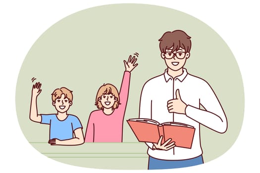 Man teacher with textbook stands near students sitting at school desk and raising hand. Father gives quality education to children by helping to prepare for exams for elementary school