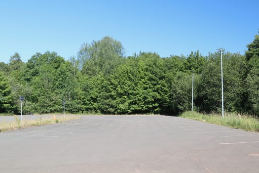 A large parking lot with green trees in the background