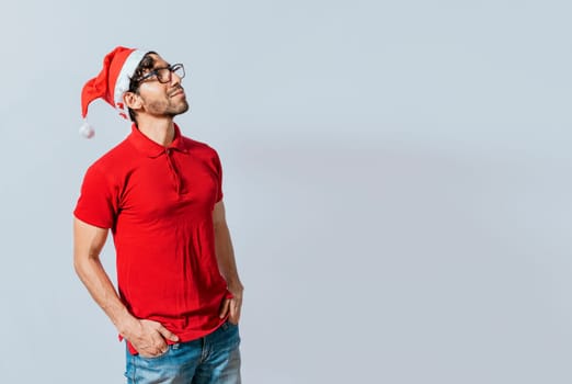 Christmas man with hand in pocket looking at copy space. Guy in Christmas hat with hands in his pocket looking at a promo, Christmas man with hands in his pocket looking at an advertisement