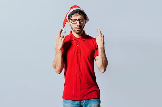 Handsome man in christmas hat making a wish on isolated background. Guy with christmas hat making a wish on isolated background, Hopeful man in christmas clothes making a wish