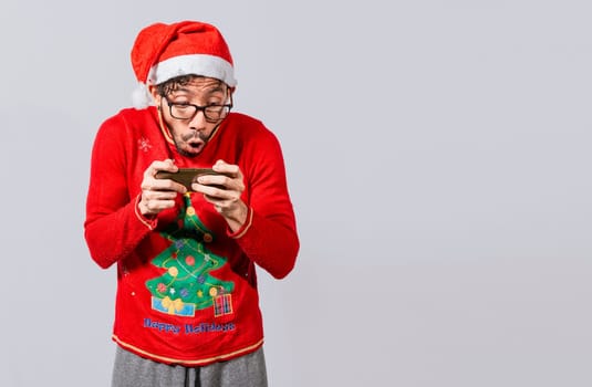 Amazed man looking at a christmas offer online, Guy looking at a christmas promo on phone. Online christmas special offers concept, Surprised people watching a christmas promotion on the phone