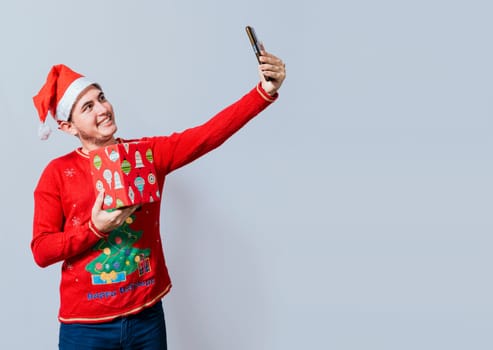 Christmas handsome man taking a selfie holding a gift isolated. Happy guy taking a christmas selfie isolated, Smiling young man in christmas hat holding a gift and taking a selfie isolated