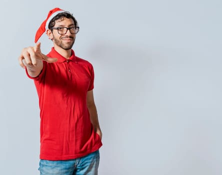 Christmas bearded man standing pointing at you isolated. Friendly guy in christmas hat with hands in his pocket pointing at you, Isolated christmas man pointing at you isolated