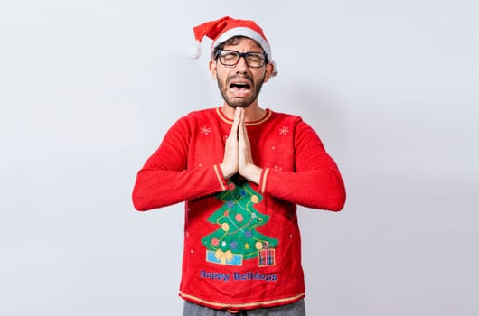Man with christmas hat with hands together in pleading gesture. Christmas guy with hands together begging for a Christmas wish, Person in christmas hat with desperate pleading gesture