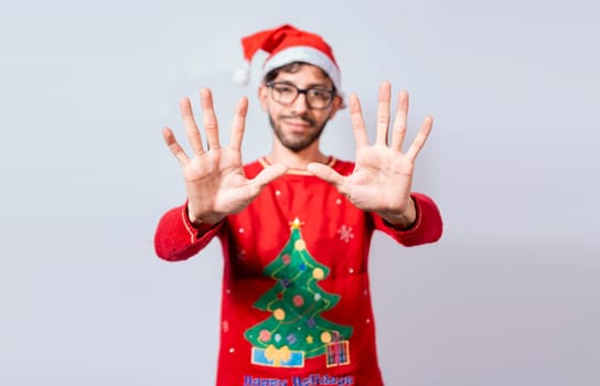 Man in christmas hat counting number ten with fingers. Christmas young man counting number ten with hands. Concept of man in christmas costume counting number ten isolated