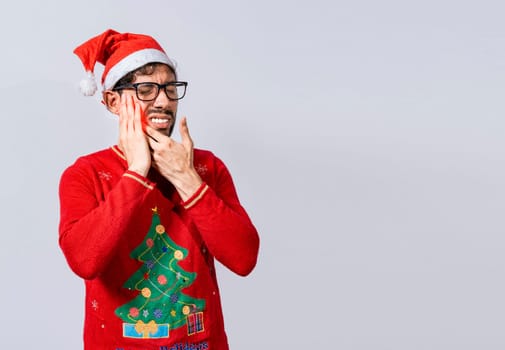 Man in christmas sweater with toothache, Young man in christmas hat with toothache isolated, Man in christmas hat in pain touching his tooth. Christmas toothache concept