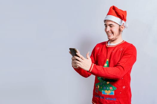 Happy guy in christmas hat smiling at cellphone isolated. People in santa hat using and smiling at cellphone isolated, Smiling young man in christmas hat using cellphone isolated