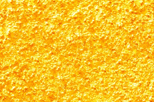 Gold yellow texture of a concrete wall. Closeup of yellow painted background of a concrete wall with a hilly uneven surface. Abstract backdrop.