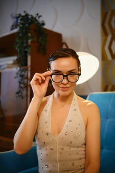 Cute woman in vintage blouse with rhinestones touching her glasses
