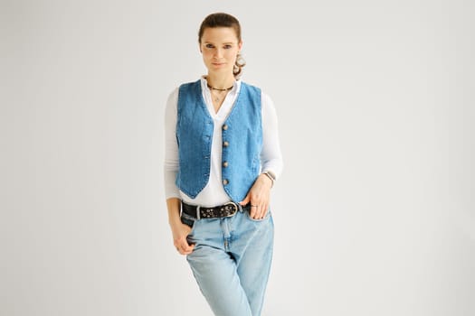 Portrait of attractive woman with smooth hair in denim vest, jeans and cotton shirt
