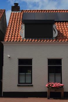 View of a residential house with two windows and flowers, blue sky in the background