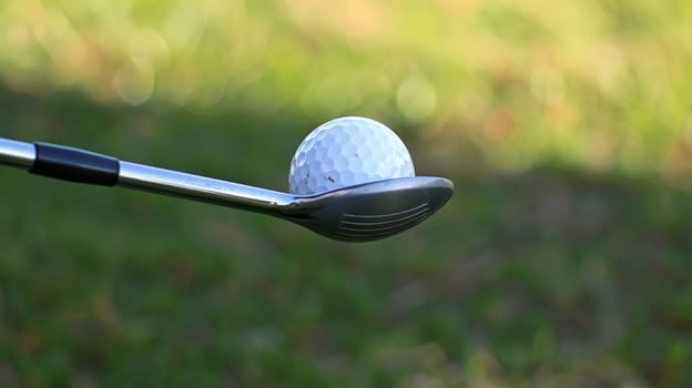 A detailed view capturing a golf club and a golf ball in close proximity, ready for a swing on the golf course. The dimpled texture of the ball contrasts with the sleek surface of the club, highlighting the anticipation of a precise shot.