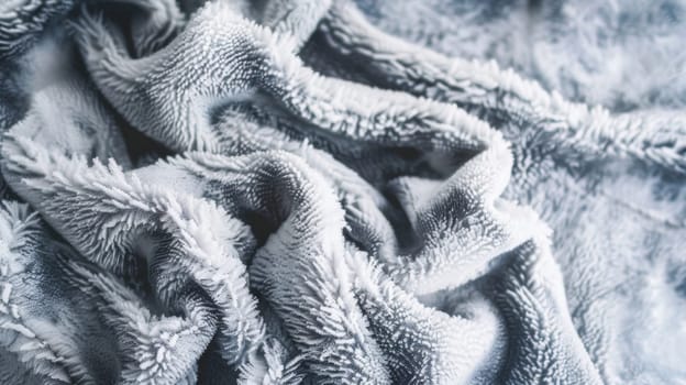 A blanket lies on the ground, completely covered in a thick layer of snow. The contrast between the black fabric and the white snow creates a stark and striking visual. The texture of the snow is emphasized against the smooth surface of the blanket.