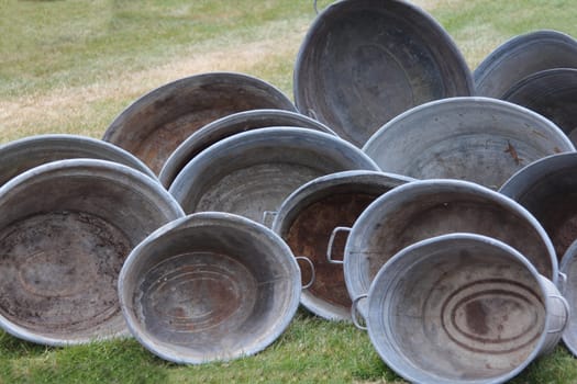 several antique zinc tubs placed on a green meadow