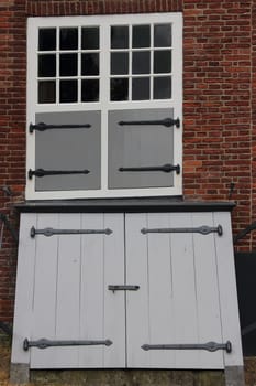 Two white windows with sprouts, in a brick wall