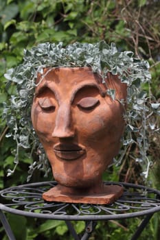 A clay head with hair from grass
