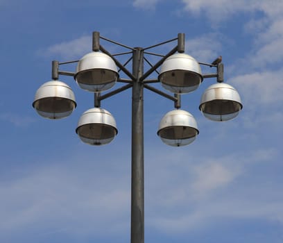 Street light with six lamps, and blue sky in the background