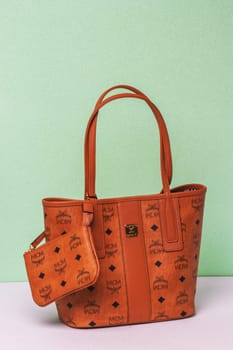 Berlin, Germany – March 29, 2024. Close-up of luxury expensive brown MCM leather handbag on a bright glitter sparkle background.