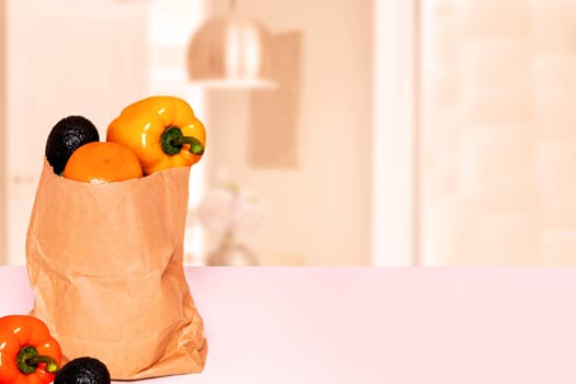 Closeup of a brown paper shopping bag with fresh vegetables and paprika on table over abstract blurred kitchen background. Space for food and product display montage. Concept of strengthening the immune system.